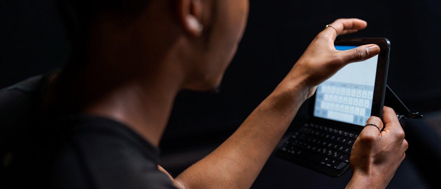 A person typing on a small tablet.